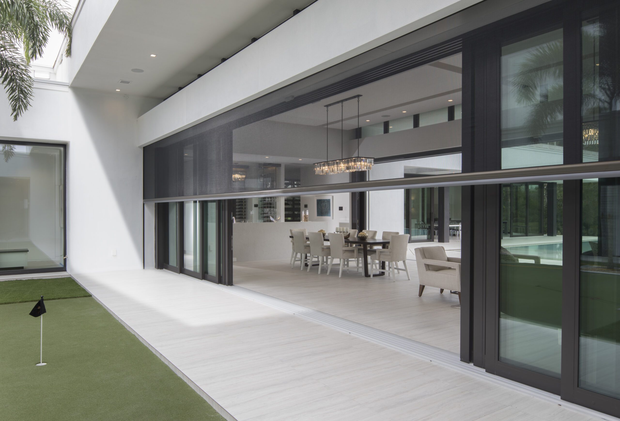 Large open-wall sliding screen system opening a modern dining area to the outdoors