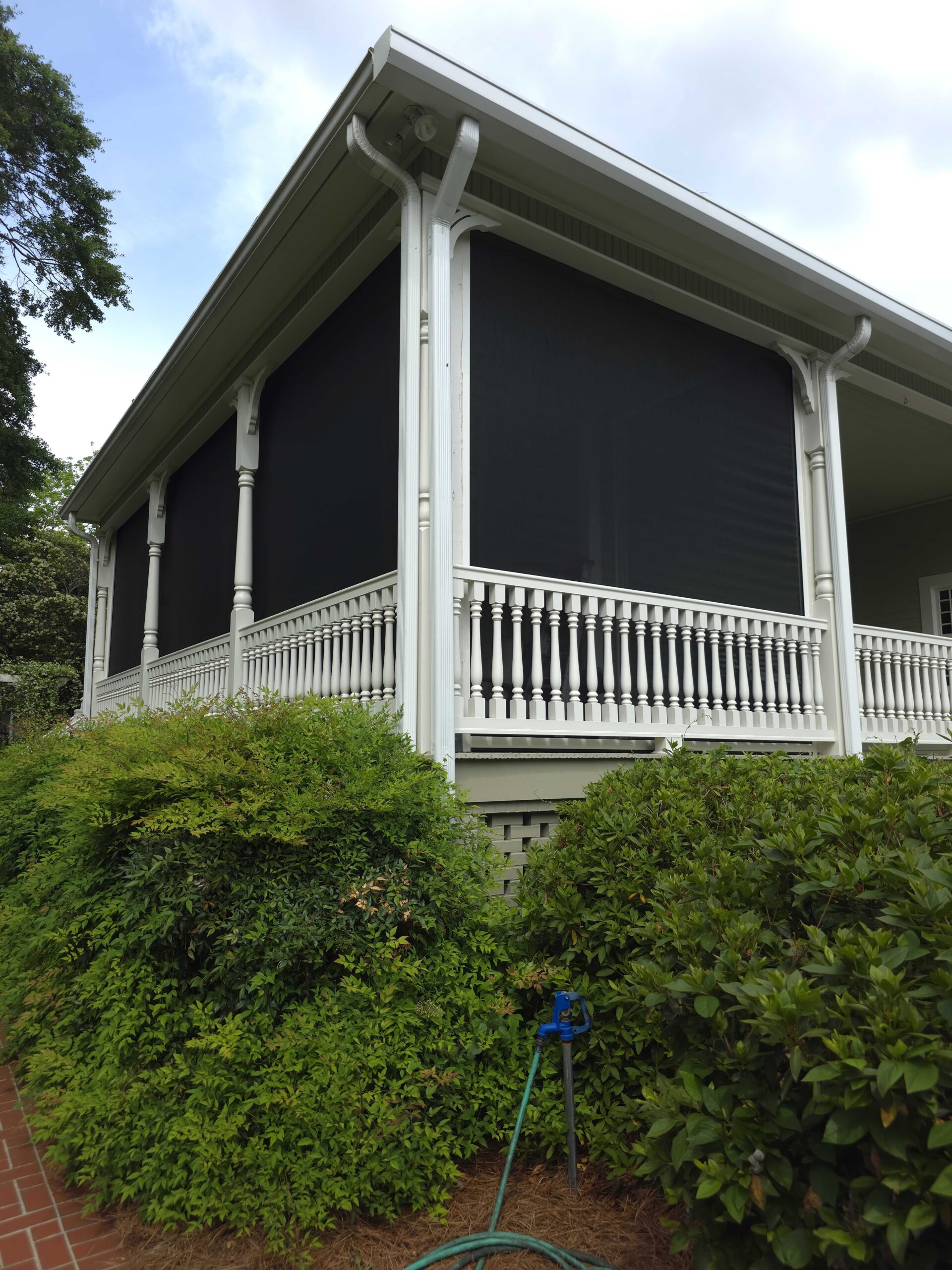 Covered porch with white railing and motorized screens