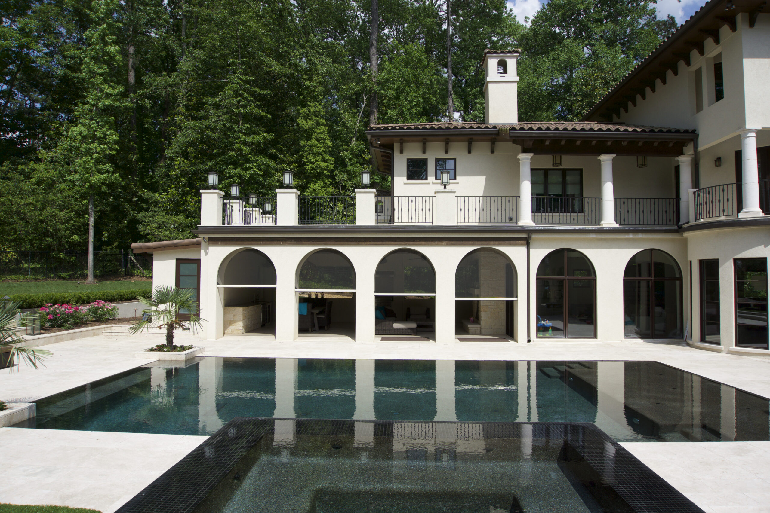 Motorized screens in the arched openings of a Mediterranean-style pool house