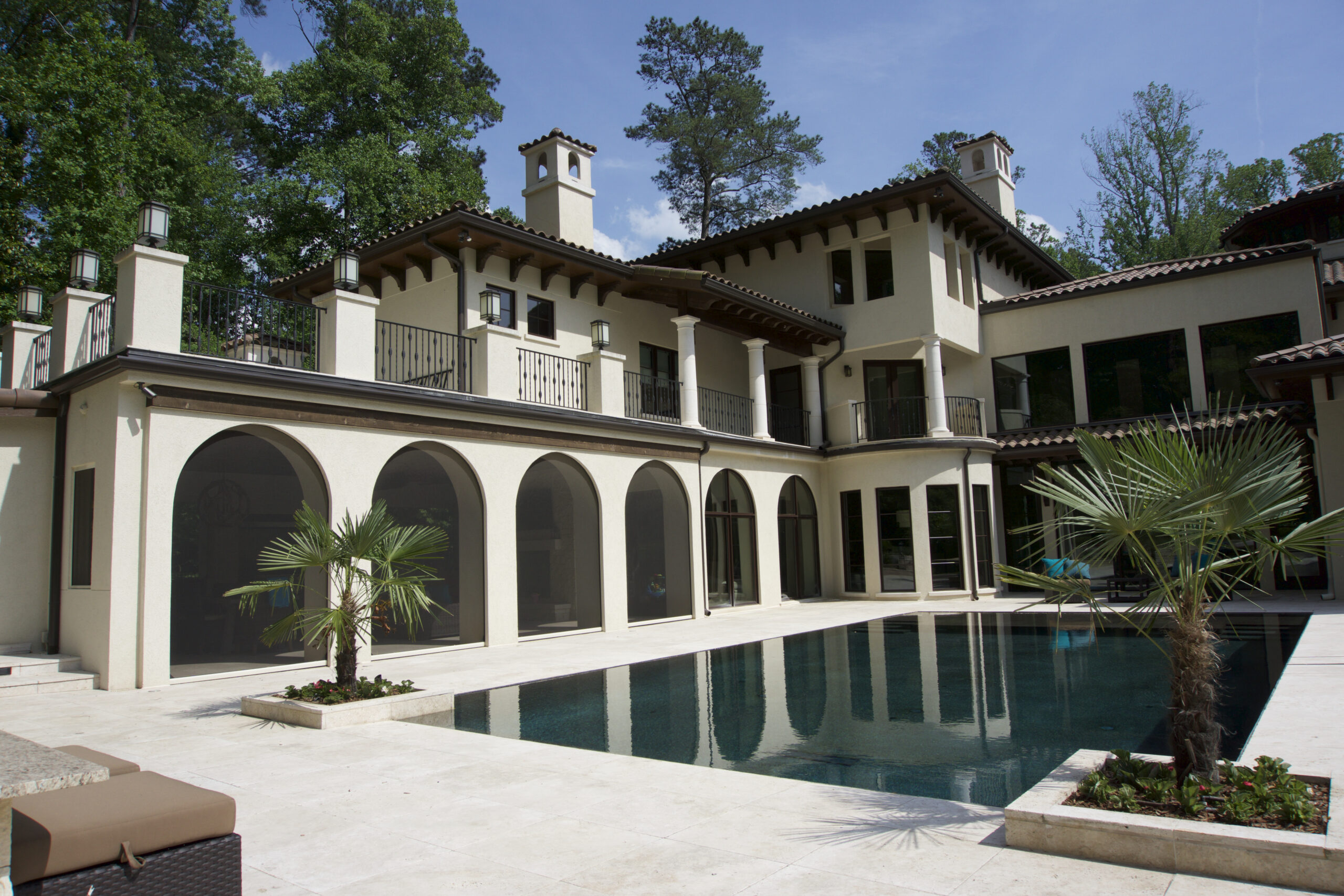 Arched veranda with motorized screens beside a pool